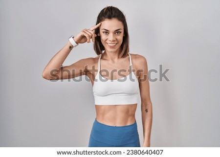 Hispanic woman wearing sportswear over isolated background smiling pointing to head with one finger, great idea or thought, good memory  Royalty-Free Stock Photo #2380640407