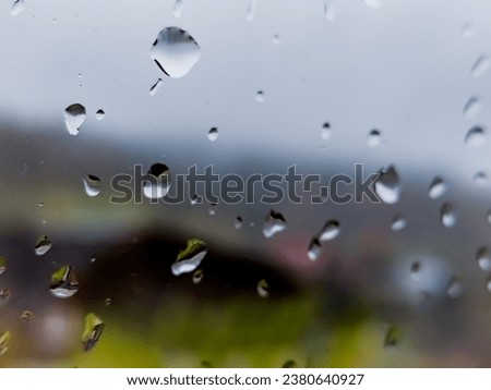 In the embrace of autumn, raindrops cling to the weathered window glass, their translucent spheres refracting the outside world. Glass captured over time gives a unique texture to this close-up image.