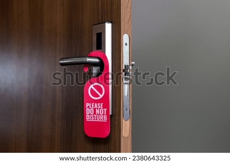 Wooden Door of hotel room with red sign please do not disturb. Composition with copy space.