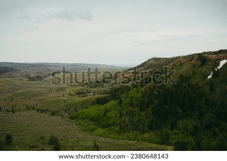 Northern Wyoming countryside in a valley overlooking the vast midwest American landscape with mountains on a crisp spring day after snowfall, with a cinematic and film-like color grade