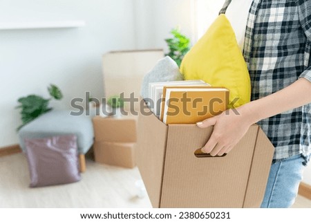 Moving house, relocation. Woman hold carton box contain equipment for new condominium, inside the room was a cardboard box containing personal belongings and furniture. move in the apartment Royalty-Free Stock Photo #2380650231