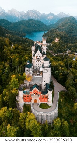 Aerial drone view Neuschwanstein castle on Alps background in vicinity of Munich, Bavaria, Germany, Europe. Autumn landscape with castle and lake in mountains covered with spruce forest Royalty-Free Stock Photo #2380656933