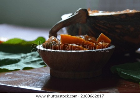 Focus on the pumpkin pieces cooked in olive oil and served in the wooden bowl. Delicious autumn recipe with chopped pumpkin
