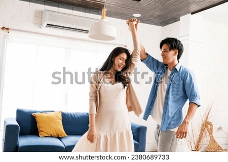 Attractive young Asian couples enjoy having a lovely romantic dance in the living room of the apartment. A family spends quality time together after moving into a new home. Image with copy space. Royalty-Free Stock Photo #2380689733