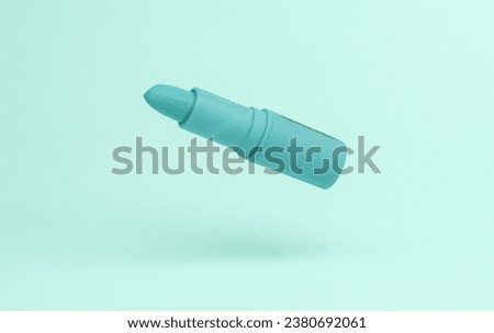 Lipstick tube flying in antigravity on blue background with shadow. Levitation object in the air. Beauty and fashion concept. Creative minimal layout