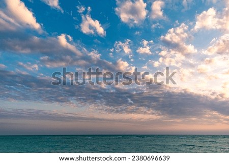 A stunning image of a sunset on the beach of Kish Island, Iran. The sun is setting behind a bank of clouds, casting a warm glow across the sky. 