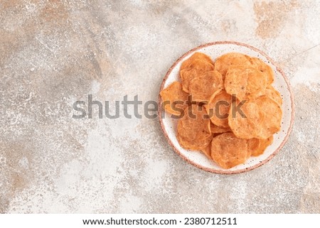 Slices of dehydrated salted meat chips with herbs and spices on gray concrete background. Top view, flat lay, copy space.