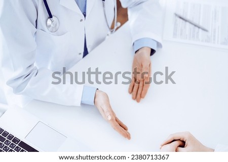 Doctor and patient discussing current health questions while sitting opposite of each other at the table in clinic, close up and above view. Medicine concept Royalty-Free Stock Photo #2380713367