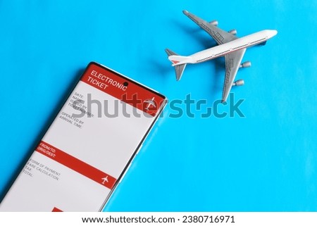 An electronic air ticket form on the screen of a mobile phone next to a toy passenger plane. The concept of buying and using an electronic air ticket for travel. Photo. Close-up