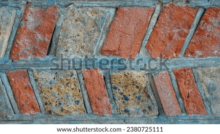Original medieval wall: Clay and gravel bricks, irregularly shaped and arranged in a herringbone pattern. Forming a stunning texture background. Wallpaper, texture design, real photo.  