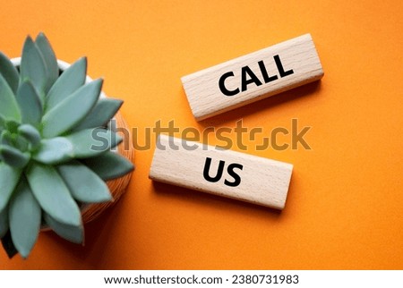 Call Us symbol. Wooden blocks with words Call Us. Beautiful orange background with succulent plant. Business and Call Us concept. Copy space.