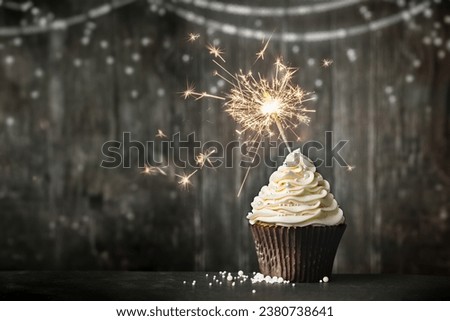 Birthday celebration cupcake with sparkler against a wooden background