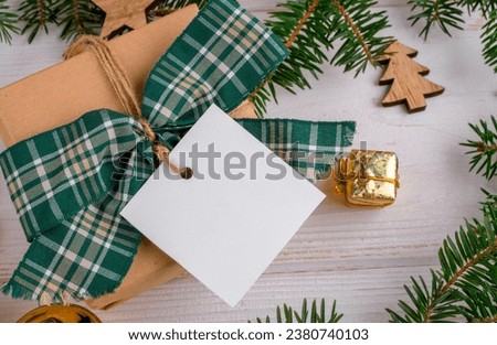 Christmas square gift tag mockup with craft wrapped gift box on a white background with border of natural fir branches, close up