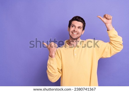 Photo of thoughtful dreamy man dressed yellow shirt looking pointing two thumbs empty space isolated purple color background