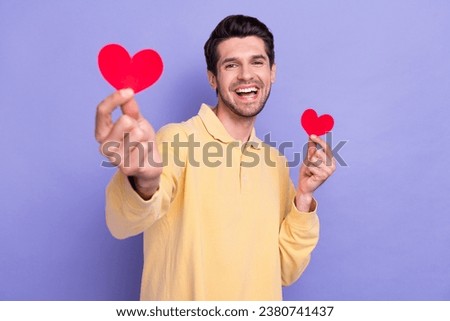 Photo of cool funky guy wear yellow shirt rising two little red hearts isolated violet color background
