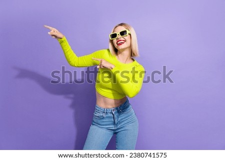 Portrait of optimistic woman with bob hairdo dressed yellow top in sunglass indicating empty space isolated on purple color background