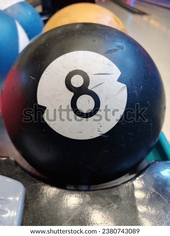 An 8-ball, positioned amidst the vibrant ambiance of a bowling alley, symbolizes the excitement of recreational sports and leisure, with striking colors and textures