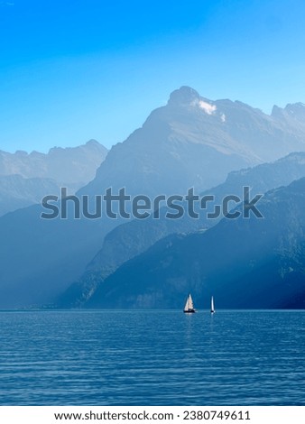 Outlines of the mountains by the swiss Lake Urnersee in the daytime hazy light. Sailboats on the lake