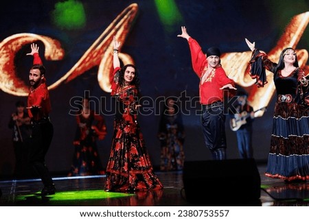 A collective of musicians, singers and dancers in gypsy costumes perform on stage. Royalty-Free Stock Photo #2380753557