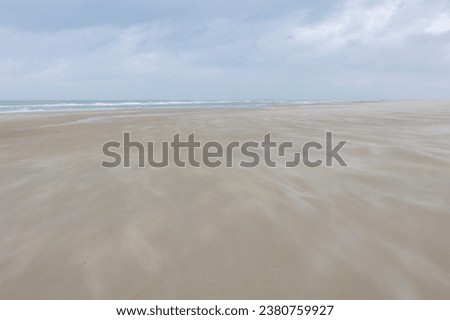 Wide and long sand beach under cloudy sky, Wind blowing the sand along the seashore of the Dutch Wadden Sea island Terschelling, A municipality and an island in the northern, Friesland, Netherlands.