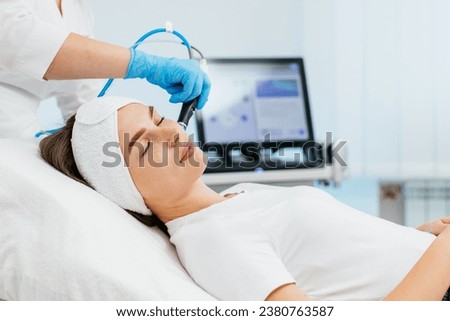 Facial skin care machine in spa clinic for anti-aging or acne treatment. The concept of aesthetic medicine, beauty tools, latest technologies in beauty industry.  Royalty-Free Stock Photo #2380763587