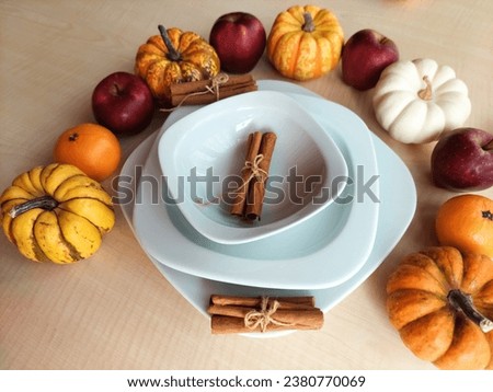 Presentation of cinnamon sticks in a set of porcelain plates among autumn harvest products on a wooden floor