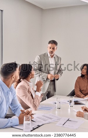 Busy senior company professional executive leader ceo manager leading business conference meeting managing consulting diverse corporate team workers at table in office board room. Vertical Royalty-Free Stock Photo #2380776445