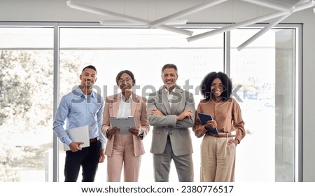 Four international successful company workers and leaders business people executive team colleagues standing in office. Happy confident diverse professional employees group corporate portrait.