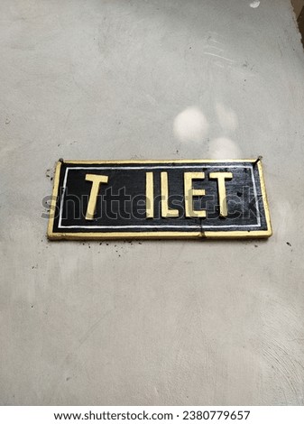 toilet sign board, withouT 'O' letter, hangging in white wall