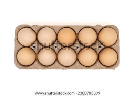 Cardboard egg box with ten chicken eggs isolated on white background with copy space. Top view or flat lay. Royalty-Free Stock Photo #2380783399