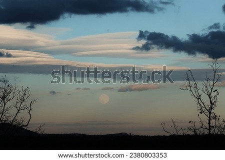 Altocumulus clouds and a rising full moon creates a dramatic Arizona sky scene Royalty-Free Stock Photo #2380803353