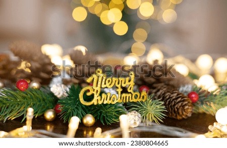 Christmas decorations, pine cones, red holly berries, and pine branches against a warm bokeh light background