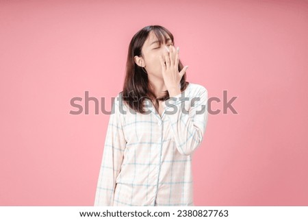 Beautiful Asian woman wearing pajamas bored yawning tired covering mouth with hand. restless and sleepiness. Royalty-Free Stock Photo #2380827763