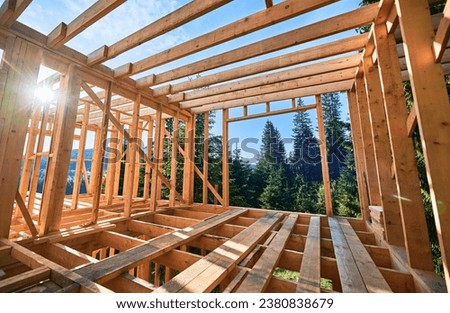 Residential wooden frame structure being erected. Initiation of fresh building endeavor for dwelling or mountain chalet. Concept of contemporary ecological construction and modern architectural style. Royalty-Free Stock Photo #2380838679