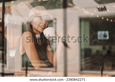 Businesswoman thinking and planning in a coffee shop. Photographed through window.
