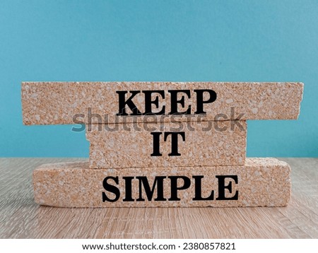 Keep it simple symbol. Concept word Keep it simple on beautiful brick blocks. Beautiful wooden table blue background. Business motivational keep it simple concept. Copy space.