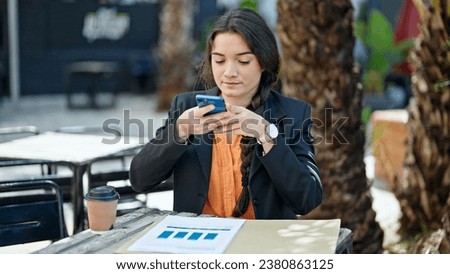 Young beautiful hispanic woman business worker making photo to documents at coffee shop terrace