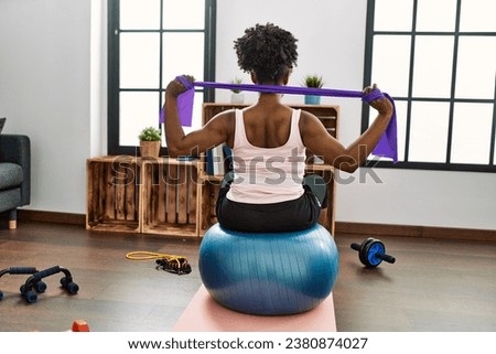 African american woman using elastic band training at home