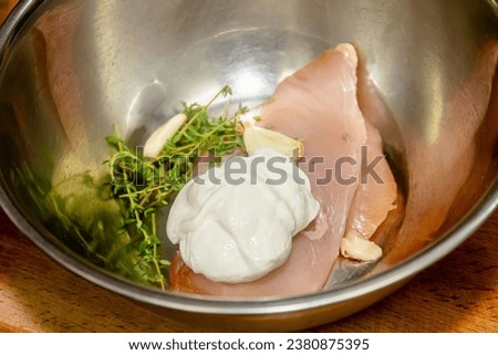 Marinated Chicken Quarters in a Cast-Iron Skillet: Uncooked chicken pieces marinated in Greek yogurt and fresh herbs Royalty-Free Stock Photo #2380875395