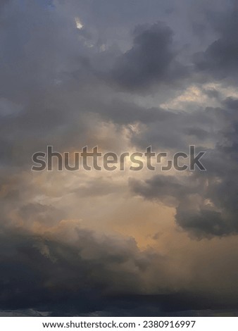 The post-storm sky: billowing orange-hued cumulus clouds intermingled with gray rainclouds, a radiant sunset casting light from within. Royalty-Free Stock Photo #2380916997