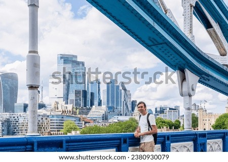 London, UK, 21 june 2023: The City of London skyline Bank Canary Wharf central financial districts skyscrapers sunny day River Thames futuristic buildings man white t-shirt portrait backpack tourist
