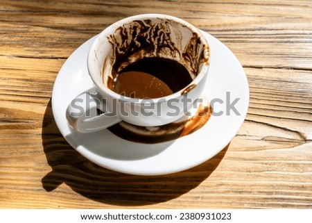 cup of Turkish coffee with grounds and patterns left after drinking on saucer after turning cup for fortune telling on wooden table in street cafe on sunny morning Royalty-Free Stock Photo #2380931023