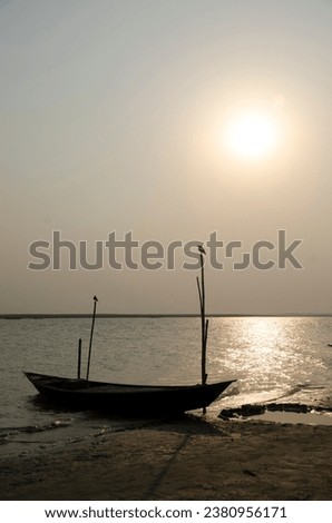 The photo of a boat anchored beside the river was captured at the time of dusk.