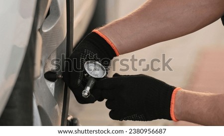 Mechanic Checks Tire Pressure Using Monometer In Close Up Shot Royalty-Free Stock Photo #2380956687
