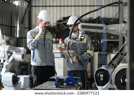 Robotics engineer working on maintenance of robotic arm in factory warehouse. Business technology.