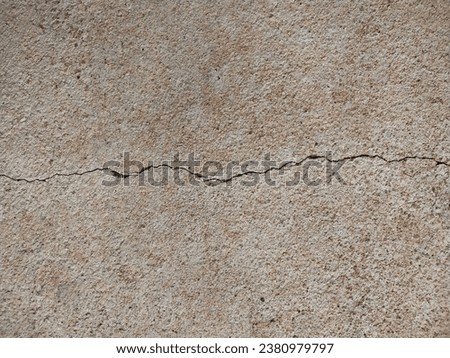The surface of the old concrete has cracks covered with red dust.
