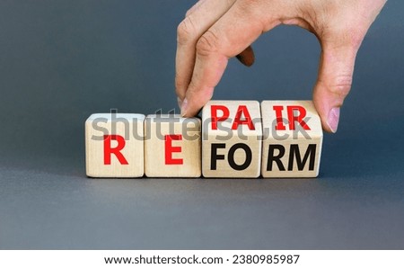 Reform and repair symbol. Concept words Reform Repair on wooden block. Beautiful grey table grey background. Businessman hand. Business reform and repair concept. Copy space.