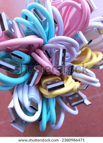pile of colorful cellphone charger cables on red background Royalty-Free Stock Photo #2380986471