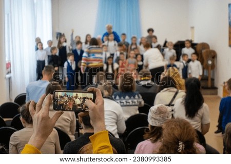 Children choir on stage with parents watching and taking pictures