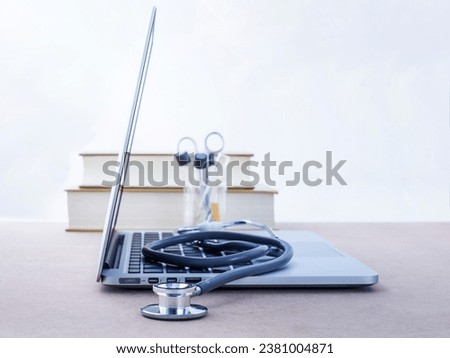 Doctor's desk with computer and medical textbook with shallow depth of field focus on stethoscope .
